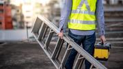 Worker carrying an aluminium ladder for safe workplace use